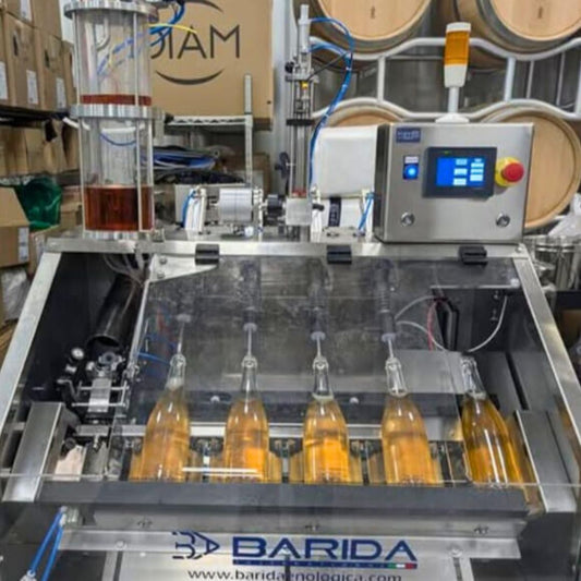 Five bottles in a semi-automatic disgorging, dosing & topping, corking & muzzling machine, with Barida branding.